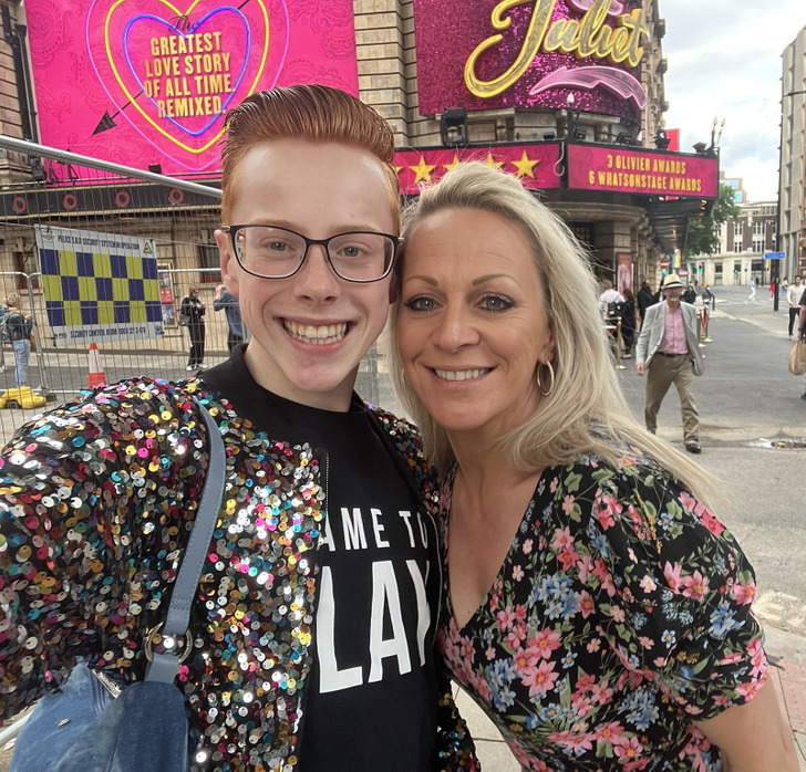 A boy and his mom takes a selfie on the street.